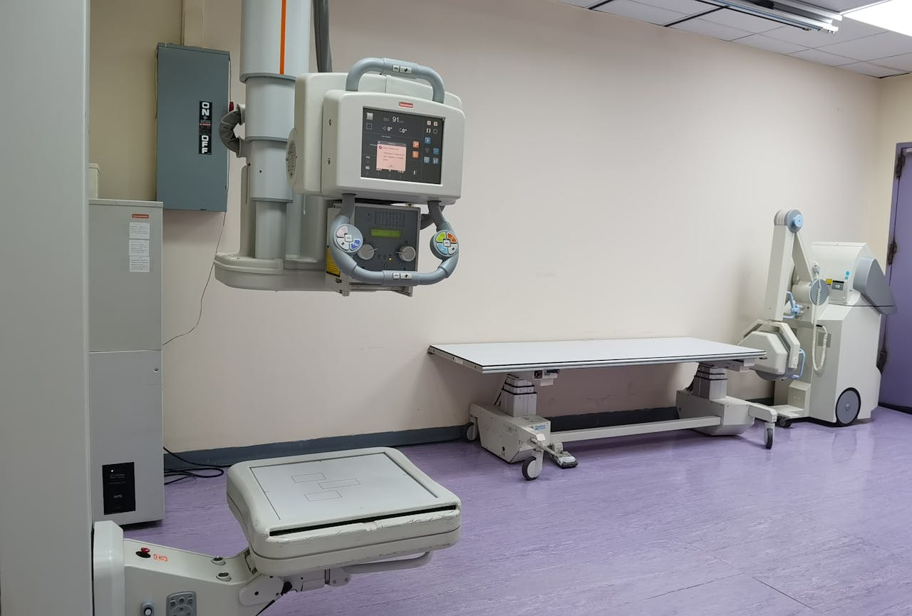 Clinical setting with X-ray machines and examination table in a healthcare facility.